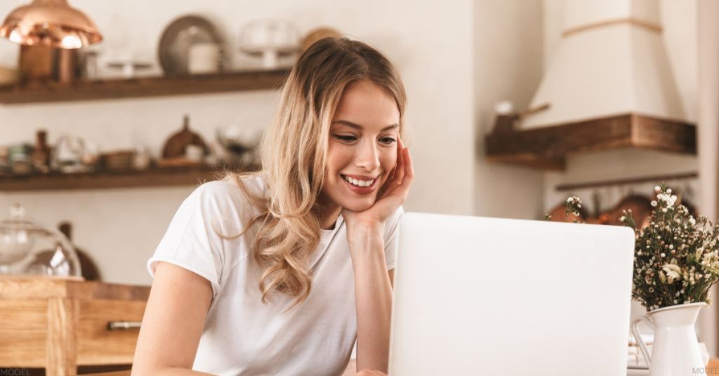 Blonde woman researching the best plastic surgeon in Toledo, Ohio on her computer (model)