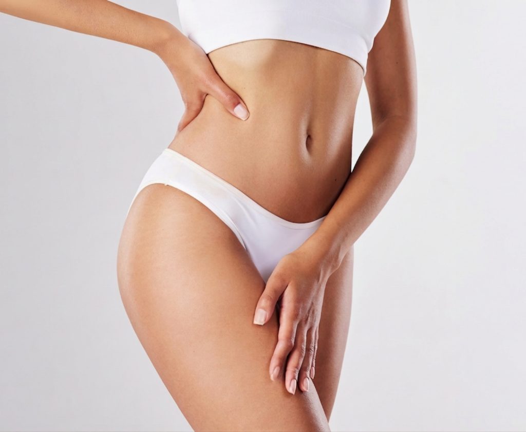 Woman posing in white underwear and a cropped top with one hand on her waist and the other resting on her thigh.